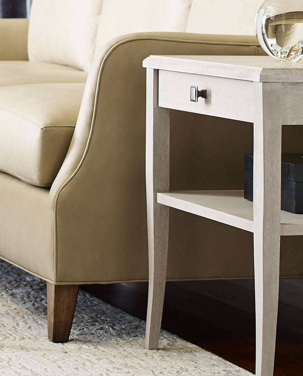 A closeup of a tan leather sofa showing the detailed tailoring of the arm and corner.